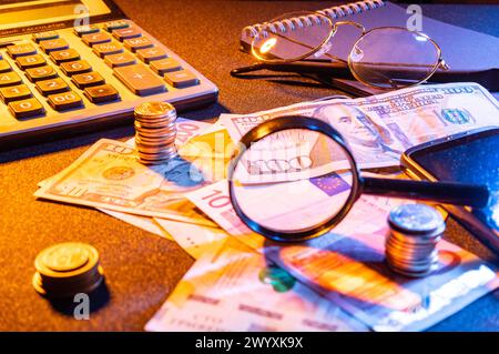 L'argent est dispersé sur la table. Billets et pièces sur la table. Vue de l'argent à travers une loupe. Banque D'Images