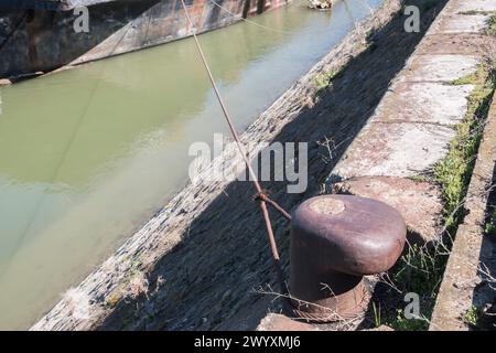 Vieux poteau d'amarrage de quai en métal avec corde d'acier pour sécuriser le navire de barge de vrac de rivière en gros plan Banque D'Images