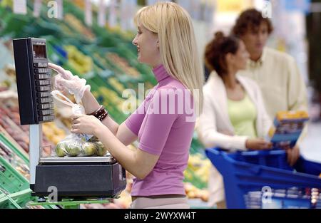 Femme pesant des fruits au supermarché. Banque D'Images