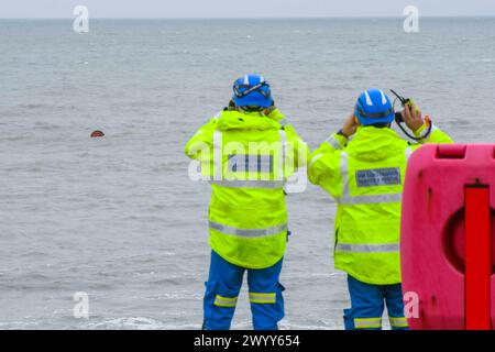 Burton Bradstock, Dorset, Royaume-Uni. 8 avril 2024. Météo britannique. Une équipe de recherche et de sauvetage des garde-côtes de HM surveillant un grand enrouleur de câble en bois flottant à 100 mètres de la plage à Burton Bradstock dans le Dorset. Le grand enrouleur de câble, qui mesure environ 6 pieds de diamètre, pourrait causer de graves dommages à un petit bateau de plaisance en cas de collision. Ces derniers jours, beaucoup de débris de palettes en bois, qui ont peut-être été lavés d'un navire pendant la tempête Kathleen, ont été lavés à terre sur les plages. Crédit photo : Graham Hunt/Alamy Live News Banque D'Images