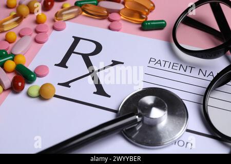 Formulaire de prescription médicale, pilules, verres et stéthoscope sur fond rose, gros plan Banque D'Images