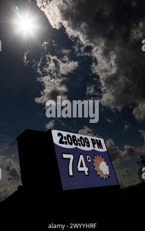Owensboro, Kentucky, États-Unis. 08 avril 2024. La lune commence à s'éloigner du soleil au-dessus d'un signe de temps et de température le long de Frederica Street après une éclipse solaire totale. Comme visible depuis Owensboro, le soleil était couvert à 99,89% par la lune lorsque l'éclipse a culminé à 14h04 HAC (GMT -5). (Crédit : Billy Suratt/Apex MediaWire via Alamy Live News) Banque D'Images