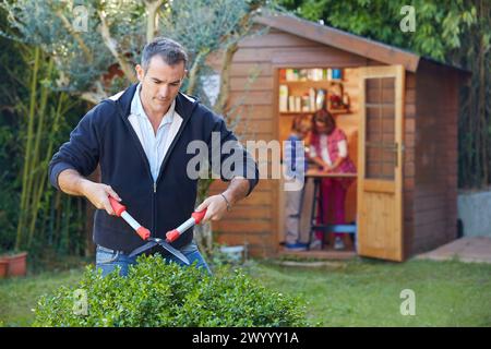 Le père et les enfants faire bricolage dans le jardin. Couper une haie. Banque D'Images