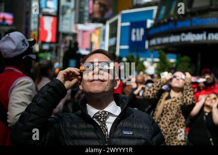 New York, États-Unis. 8 avril 2024. Les gens regardent une éclipse solaire dans le quartier de Times Square à New York, aux États-Unis, le 8 avril 2024. Une éclipse solaire totale balayait l'Amérique du Nord lundi, alors que les résidents et les visiteurs se rassemblaient à différents endroits sur le chemin de l'éclipse pour regarder et encourager. L'éclipse solaire totale -- surnommée la Grande éclipse américaine pour son long chemin au-dessus de l'Amérique du Nord -- était visible dans le ciel au-dessus de certaines parties du Mexique, de 15 états américains et de l'est du Canada. Crédit : Michael Nagle/Xinhua/Alamy Live News Banque D'Images