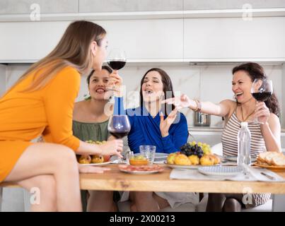 Des femmes heureuses se sont rassemblées autour d’une table festive, participant à des discussions animées et profitant des délices du vin Banque D'Images