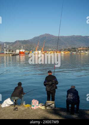 Pêcheurs avec de longues cannes à pêche sur la jetée. Un passe-temps tranquille. Pêche locale. Port de Batumi. Morsure de printemps Banque D'Images