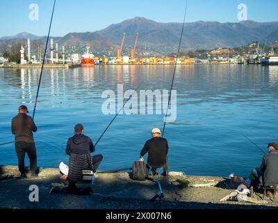 Pêcheurs avec de longues cannes à pêche sur la jetée. Un passe-temps tranquille. Pêche locale. Port de Batumi. Morsure de printemps Banque D'Images