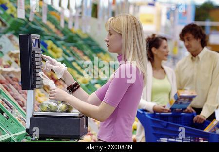 Femme pesant des fruits au supermarché. Banque D'Images