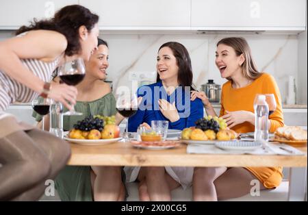 Des femmes heureuses se sont rassemblées autour d’une table festive, participant à des discussions animées et profitant des délices du vin Banque D'Images