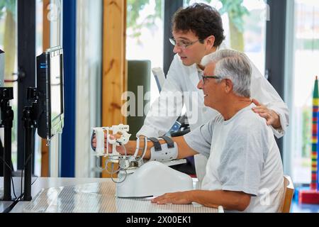 Thérapeute et patient avec robot d’assistance pour la rééducation des membres supérieurs, le robot ArmAssist permet un entraînement passif, assisté et actif du bras et de la main, permettant le traitement de la plupart des patients atteints d’AVC. Dispositif médical pour traitement neurologique. La plate-forme logicielle permet une évaluation à distance des progrès du patient et une gestion de la thérapie basée sur des jeux sérieux, qui motivent les patients à participer activement à leur rééducation et à maximiser. The Outcome, unité de technologie de la santé, Tecnalia Research & innovation, Adacen, Centre de traitement et de réadaptation des lésions cérébrales, M. Banque D'Images