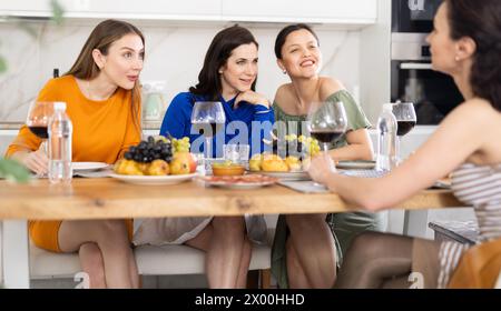 Des femmes heureuses se sont rassemblées autour d’une table festive, participant à des discussions animées et profitant des délices du vin Banque D'Images