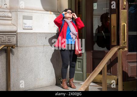 NEW YORK, NEW YORK - 08 AVRIL : les gens regardent une éclipse solaire partielle sur la 5e Avenue le 8 avril 2024 à New York. Avec la première éclipse solaire à traverser l’Amérique du Nord en sept ans, New York ne se trouvait pas sur le chemin de la totalité, avec seulement 90% du soleil couvert par la lune ; la prochaine éclipse visible aux États-Unis sera en 2044. Banque D'Images