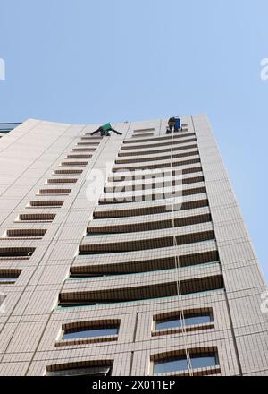Nettoyeurs de vitres d'accès à la corde nettoyant les vitres d'un grand bâtiment à Deira, Dubaï, Émirats arabes Unis. Banque D'Images