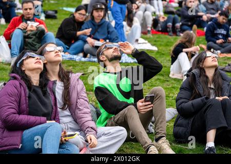 Toronto, Canada. 08 avril 2024. Les gens regardent le début de l'éclipse solaire partielle à Riverdale Park, portant leurs lunettes d'éclipse spéciales. Le 8 avril 2024, Toronto assistera à une éclipse solaire partielle, avec une couverture solaire d'environ 85 %. Les Skywatchers de la ville observeront la lune qui passe entre la Terre et le soleil, créant une atténuation notable de la lumière du soleil pendant l'événement. Crédit : SOPA images Limited/Alamy Live News Banque D'Images