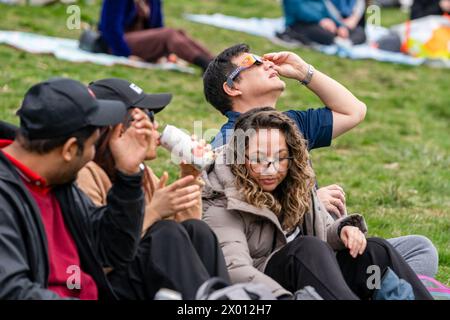 Toronto, Canada. 08 avril 2024. Les gens regardent le début de l'éclipse solaire partielle à Riverdale Park, portant leurs lunettes d'éclipse spéciales. Le 8 avril 2024, Toronto assistera à une éclipse solaire partielle, avec une couverture solaire d'environ 85 %. Les Skywatchers de la ville observeront la lune qui passe entre la Terre et le soleil, créant une atténuation notable de la lumière du soleil pendant l'événement. Crédit : SOPA images Limited/Alamy Live News Banque D'Images