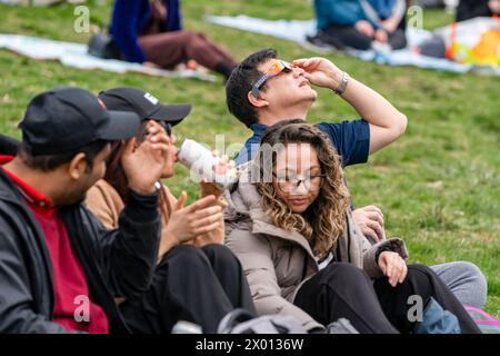 Toronto, Canada. 08 avril 2024. Les gens regardent le début de l'éclipse solaire partielle à Riverdale Park, portant leurs lunettes d'éclipse spéciales. Le 8 avril 2024, Toronto assistera à une éclipse solaire partielle, avec une couverture solaire d'environ 85 %. Les Skywatchers de la ville observeront la lune qui passe entre la Terre et le soleil, créant une atténuation notable de la lumière du soleil pendant l'événement. (Photo de Shawn Goldberg/SOPA images/SIPA USA) crédit : SIPA USA/Alamy Live News Banque D'Images