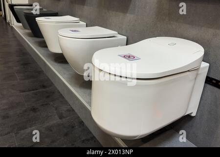 Cuvettes de toilette en céramique de différents types sur une vitrine de magasin. Vente de matériel sanitaire dans un magasin spécialisé. Banque D'Images