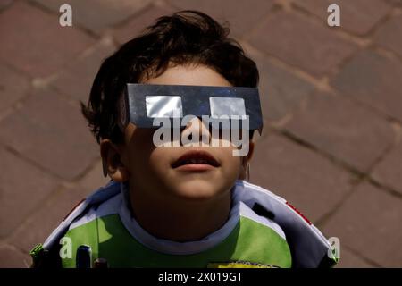 Non exclusif : un garçon observe l'éclipse solaire à travers des lunettes spéciales pendant la Grande éclipse solaire nord-américaine à Mexico, Mexique. Perso Banque D'Images