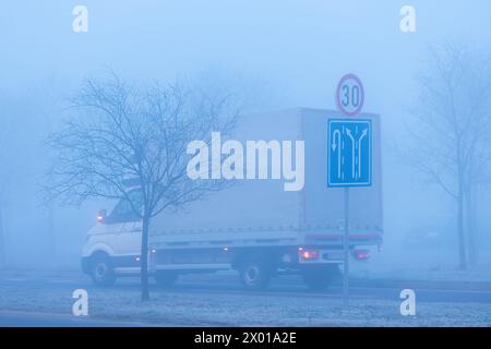 Trafic dans le brouillard, panneaux routiers et camion sur l'autoroute, mise au point sélective Banque D'Images