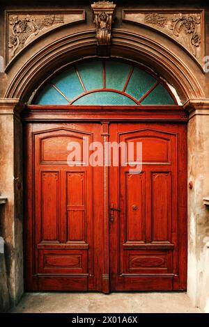 Porte en bois vintage massive comme entrée d'un ancien bâtiment résidentiel avec façade décorée en béton moulé, image verticale Banque D'Images