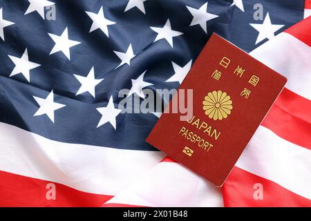 Passeport japonais sur fond de drapeau national des États-Unis gros plan. Tourisme et concept de diplomatie Banque D'Images