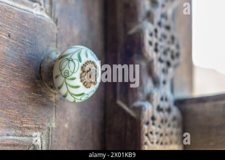 Détail étroit d'une poignée de volet de fenêtre en céramique peinte d'une maison arabe traditionnelle restaurée. Banque D'Images