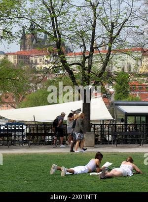 Les touristes se reposent dans un parc devant le château de Prague près de la rivière Vltava, au quai Alsovo à Prague, République tchèque, le 8 avril 2024. (CTK photo/Milos Ruml) Banque D'Images