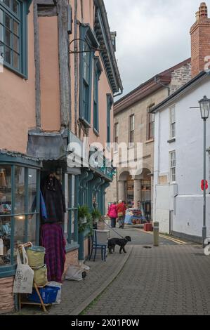 La vue le long de Market Street à Hay-on-Wye, Powys, pays de Galles, Royaume-Uni, montrant de vieilles façades de magasins à ossature de bois avec le marché aux fromages au loin. Banque D'Images