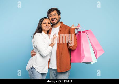 Couple embrassant avec des sacs à provisions sur fond bleu Banque D'Images