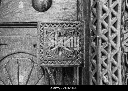 Image monochrome, filtrée, à focale étroite d'un détail sculpté d'une porte en bois à l'entrée d'une maison arabe traditionnelle restaurée. Banque D'Images