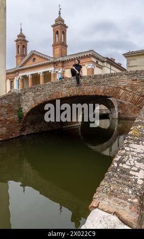 Femme sur le pont devant la cathédrale San Cassiano à Comacchio dans la province de Ferrare dans la région d'Emilie-Romagne en Italie Banque D'Images