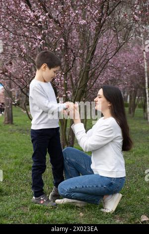 Fils donne à sa mère une petite fleur de cerisier en fleur au printemps Banque D'Images