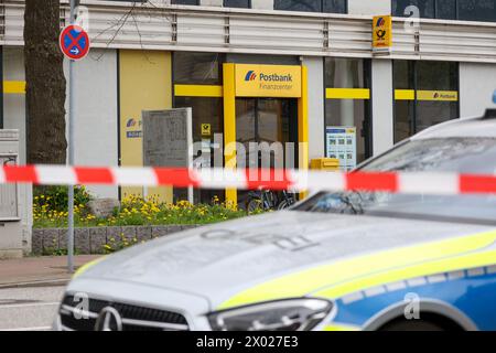 Hambourg, Allemagne. 09th Apr, 2024. Des policiers de Hambourg se tiennent devant une succursale de la Postbank à Hamburg-Lurup pendant une opération. Une succursale de la banque postale du Lurup-Center de Hambourg et des rues environnantes a été bouclée mardi matin et des unités d'élimination des explosifs ont été appelées. Crédit : Bodo Marks/dpa/Alamy Live News Banque D'Images