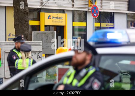 Hambourg, Allemagne. 09th Apr, 2024. Des policiers de Hambourg se tiennent devant une succursale de la Postbank à Hamburg-Lurup pendant une opération. Une succursale de la banque postale du Lurup-Center de Hambourg et des rues environnantes a été bouclée mardi matin et des unités d'élimination des explosifs ont été appelées. Crédit : Bodo Marks/dpa/Alamy Live News Banque D'Images