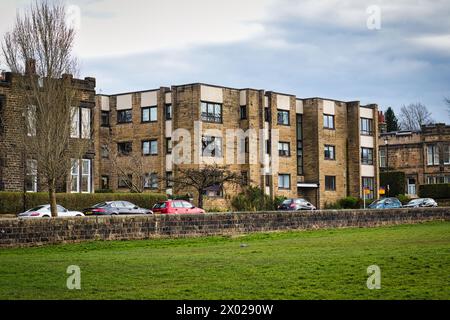 Immeubles résidentiels modernes avec des voitures garées devant, derrière un mur de pierre avec une pelouse verte luxuriante au premier plan. Concept de vie urbaine i Banque D'Images