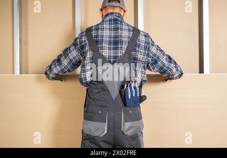 Travailleur de chantier de construction installant la feuille d'une cloison sèche Banque D'Images