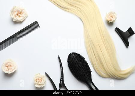 Composition de pose plate avec différents outils de coiffeur et fleurs sur fond blanc, espace pour le texte Banque D'Images