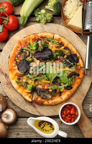 Délicieuse pizza végétarienne et ingrédients sur table en bois, plat Banque D'Images