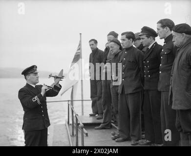 YACHT D'INSTRUCTION DEMS MOBILE. 23 FÉVRIER 1942, À BORD DU MY MELITA, BAIE DE GOUROCK. LE LANCEMENT MOTORISÉ EST LE PREMIER LANCEMENT INSTRUCTIF À ÊTRE UTILISÉ POUR L'ÉQUIPEMENT DÉFENSIF DES NAVIRES MARCHANDS AU ROYAUME-UNI. IL EFFECTUE DES TRAJETS QUOTIDIENS JUSQU'AUX MOUILLAGES POUR TENIR LES MARINS MARCHANDS INFORMÉS ET INSTRUITS DES DERNIÈRES AMÉLIORATIONS POUR LA DÉFENSE DE LEURS NAVIRES. - Une classe de reconnaissance d'avion à bord du Motor Launch Banque D'Images