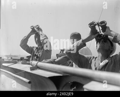 DÉBARQUEMENTS DANS LE SUD DE LA FRANCE. 14 ET 15 AOÛT 1944, À BORD DU PORTE-AVIONS D'ESCORTE HMS PURSUER EN MER. - Capitaine H. R. Graham, DSO, DSC, RN, commandant du POURSUIVANT, observant avec les officiers du navire sur le pont alors que les bombardiers alliés rugissaient au-dessus de la tête pour attaquer les positions ennemies à terre Banque D'Images