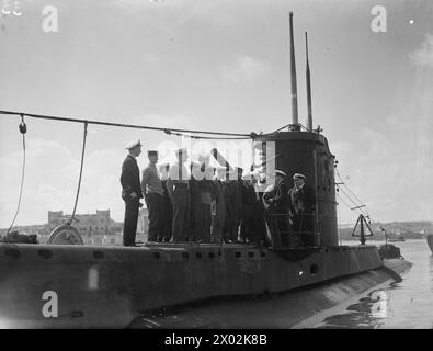 « VIE SOUS-MARINE » : TÂCHES DE DERNIÈRE MINUTE DEVANT UNE PATROUILLE MÉDITERRANÉENNE. MARS ET AVRIL 1943, MALTE, OFFICIERS ET HOMMES D'UN SOUS-MARIN BRITANNIQUE AVANT DE PARTIR EN PATROUILLE EN MÉDITERRANÉE. - Équipage de service de sous-marin, aligné sur le tubage, recevant leurs ordres quotidiens sur la routine de travail par le coxswain Banque D'Images