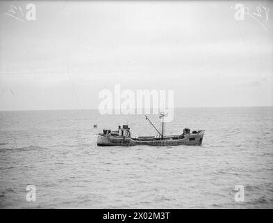 LE HMS KELVIN SAUVE LES PRISONNIERS DE GUERRE ÉVADÉS, METTANT FIN À CINQ MOIS DE SENSATIONS FORTES ET D'AVENTURES. DÉCEMBRE 1940, À BORD DU HMS KELVIN. DIX-HUIT HOMMES DEBOUT SUR LE PONT D'UN CARGO NEUTRE, ONT ACCLAMÉ LE KELVIN ALORS QU'IL VENAIT DE LES SAUVER, ET ONT MIS FIN À CINQ MOIS D'AVENTURES POUR TREIZE DES DIX-HUIT HOMMES SAUVÉS. LES TREIZE MEMBRES DE LA 51E DIVISION HIGHLAND FURENT CAPTURÉS EN JUIN 1940 LORS DE L'AVANCE ALLEMANDE SUR LA SOMME. UNE NUIT, DIRIGÉS PAR LEUR COMMANDANT, ILS S'ÉCHAPPENT, ATTEIGNANT FINALEMENT VICHY OÙ ILS PARVIENNENT À OBTENIR DES UNIFORMES MILITAIRES FRANÇAIS. DE VICHY ILS ONT FAIT LEUR WA Banque D'Images