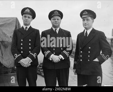 « ŒIL MAGIQUE » DU DESTROYER BRITANNIQUE. 14 NOVEMBRE 1943, ROSYTH. HMS BROADWAY, ANCIENNEMENT USS HUNT, CONSTRUIT À NEWPORT NEWS, EN VIRGINIE, EN 1920, ET EST L'UN DES 50 DESTROYERS REMIS AUX BRITANNIQUES PAR L'AMÉRIQUE EN ÉCHANGE DE BASES, A PEINT SUR SES ARCS LE «ŒIL MAGIQUE», ISSU D'UNE VIEILLE SUPERSTITION CHINOISE QUI REPOUSSE LE MAL. - Officiers de BROADWAY, de gauche à droite : lieutenant P W Grifin, RNR (navigateur), de Bristol ; lieutenant G P W Edwards, RN (commandant) d'Exeter ; lieutenant A P Tompkins, RNVR (premier lieutenant) de Southend Banque D'Images