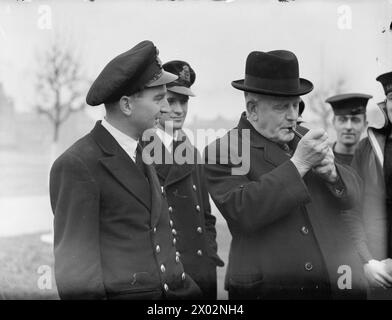 LE HAUT COMMISSAIRE REND VISITE AUX NÉO-ZÉLANDAIS À PORTSMOUTH. 4 DÉCEMBRE 1943. M. W J JORDAN, HAUT-COMMISSAIRE NÉO-ZÉLANDAIS, ACCOMPAGNÉ DE M. S R SKINNER, OFFICIER DES AFFAIRES NAVALES NÉO-ZÉLANDAISES À LONDRES, A RENCONTRÉ ET PARLÉ AVEC DES NÉO-ZÉLANDAIS SERVANT À BORD DE NAVIRES DE GUERRE. - M. Jordan allumant sa pipe en parlant avec ses compatriotes Banque D'Images