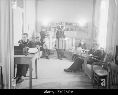 DANS UN CENTRE NAVAL D'ÉDUCATION DES ADULTES. FÉVRIER 1945, NAPLES. - Dans la bibliothèque et la salle de repos. Les livres sont sélectionnés par une notation et un officier tandis qu'un Wren fait de la broderie et une autre notation types une lettre à la maison Banque D'Images