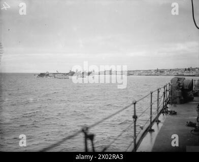 LE HMS HERMIONE EN PATROUILLE DANS L'ATLANTIQUE, ESCORTANT LE SOUS-MARIN HMS REGENT ENDOMMAGÉ PAR LES INTEMPÉRIES. 24 JANVIER 1942, À BORD DU CROISEUR HMS HERMIONE. LE SOUS-MARIN A ÉTÉ EMMENÉ À PONTA DELGADO, UN PORT NEUTRE DES AÇORES PORTUGAISES, POUR 24 HEURES DE RÉPARATIONS. - L'entrée du port de Ponta Delgado. Sur la gauche, on peut voir les navires marchands britanniques et le nouveau quai en construction Banque D'Images