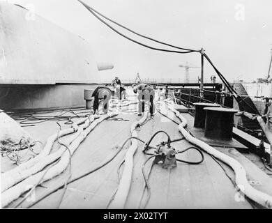 Des ouvriers installent et entretiennent des câbles de démagnétisation à bord du HMS Repulse lors de sa remise en cale sèche 1940. Banque D'Images