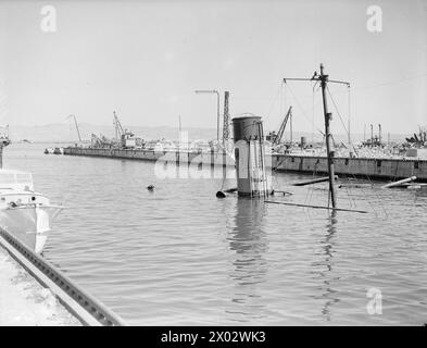 COMMENT LES FORCES AÉRIENNES ALLIÉES ONT MITRAILLÉ FERRYVILLE. 13 MAI 1943, FERRYVILLE, CHANTIER NAVAL FRANÇAIS, PRÈS DE BIZERTE. LE PORT DE FERRYVILLE A OBTENU SA PART DU BLITZ ALLIÉ PRESQUE SANS ESCALE SUR LES POINTS D’APPROVISIONNEMENT DE L’AXE QUI ONT PRÉCÉDÉ LA DÉFAITE TOTALE DE L’ALLEMAGNE ET DE L’ITALIE EN AFRIQUE. - Une des cales sèches ; un navire sabordé et les écluses ont explosé Banque D'Images