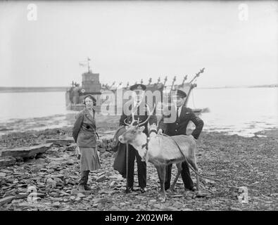 RENNES PRÉSENTÉS À ADMIRAL WELLS (ACOS). DÉCEMBRE 1943, SCAPA FLOW. L'AMIRAL WELLS, COMMANDANT DES ORCADES ET DES SHETLANDS, A REÇU 'OLGA', UN RENNE DE 3 MOIS, COMME CADEAU DE NOËL DE L'AMIRAL GOLOVKO, COMMANDANT EN CHEF DE LA FLOTTE DU NORD, AUX AUTORITÉS NAVALES BRITANNIQUES À SCAPA FLOW. OLGA A FAIT LE VOYAGE DEPUIS LA RUSSIE À BORD D'UN CROISEUR BRITANNIQUE FAISANT UNE COURSE DE ROUTINE VERS LE SUD. - L'amiral Sir Lionel Wells et Lady Wells avec Olga et son gardien, P/O Dowdeswell Banque D'Images