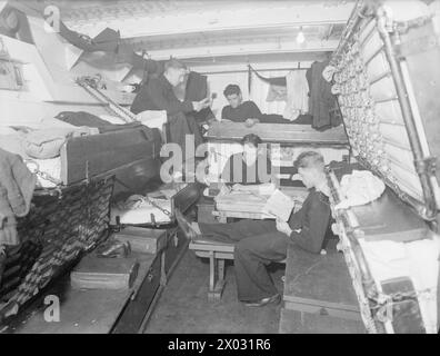 En juillet 1943, le HMT Stella Pegasi escorte le navire Pole Star tout en transportant des stocks et des fournitures aux équipages des phares le long de la côte. Les membres de l'équipage ont été photographiés sur le messdeck entre les montres. Banque D'Images